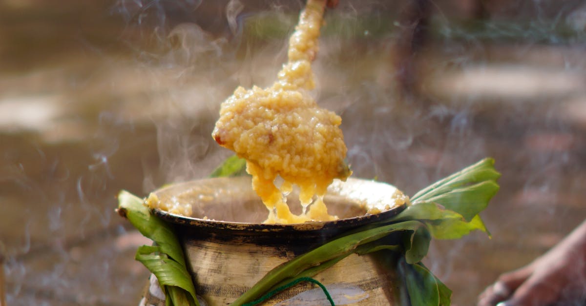 Hand stirring Pongal in a traditional pot during South Indian festival celebration.